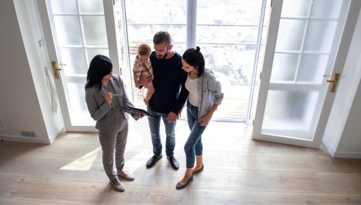 A real estate agent showing a home to a young couple and child