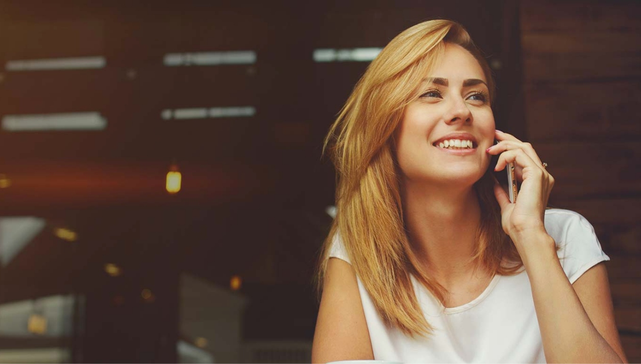 A woman speaking on a phone with a content expresion on her face
